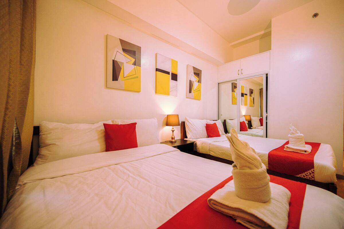 Una habitación de hotel con dos camas, un espejo y obras de arte en la pared.