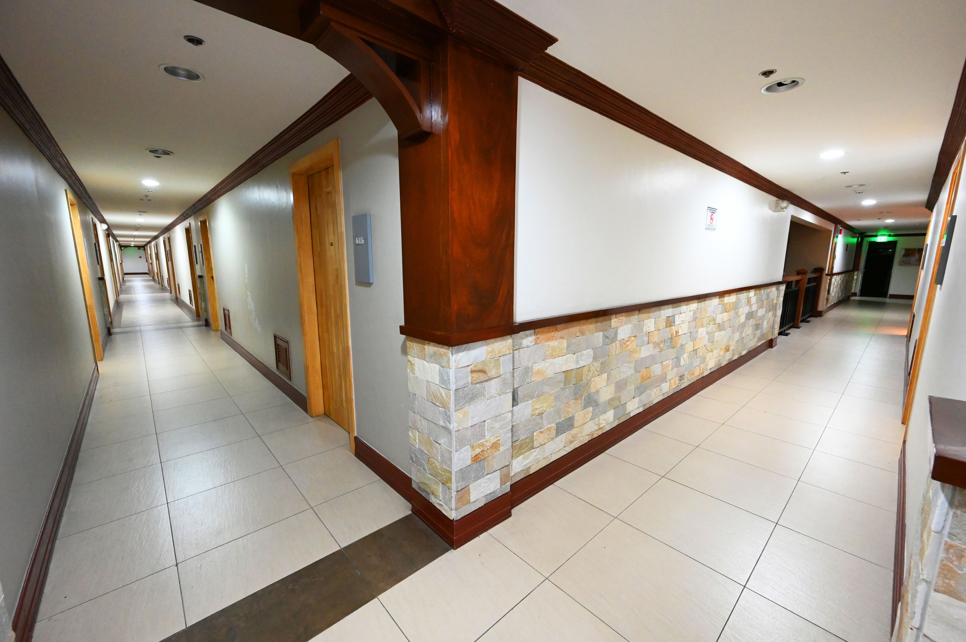 A long, narrow hallway with a stone accent wall and wooden trim.