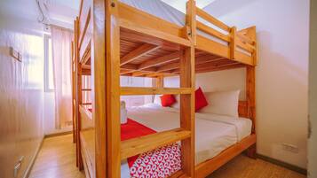 A bunk bed with a wooden frame, white bedding, and red pillows.