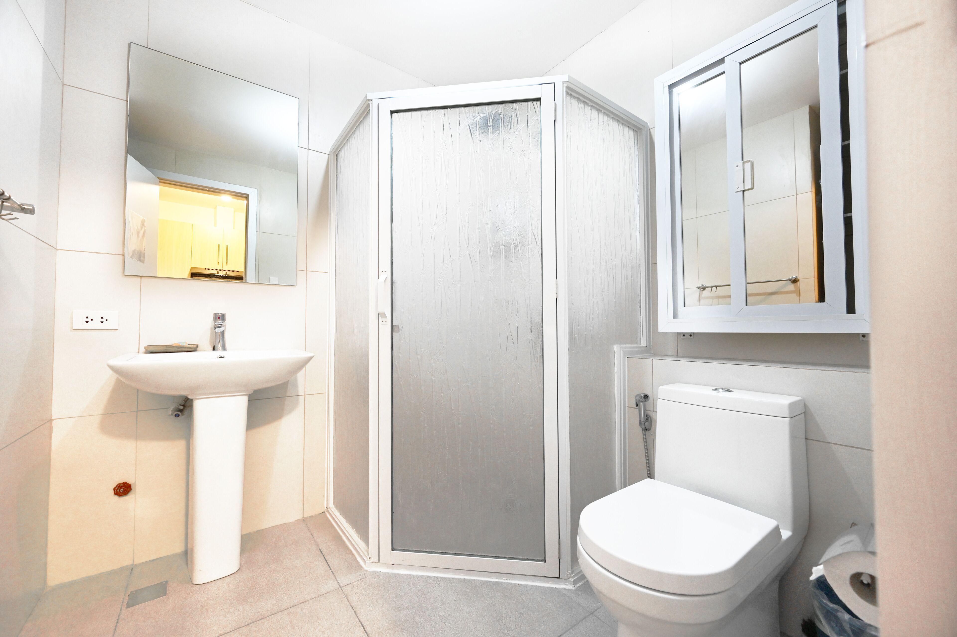 A modern bathroom with a white sink, a toilet, and a glass-enclosed shower.