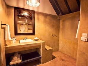 Ein Badezimmer mit Holztisch, Spiegel und Duschbereich.