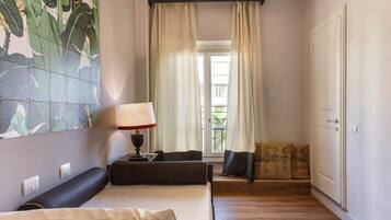 A hotel room with a bed, a nightstand, a lamp, a window with curtains, and a view of the outside.