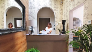 A reception area with a wooden reception desk, a mirror, and a potted plant. - Boutique Hotel Hugo (Florence)