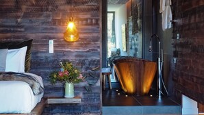 Une salle de bain moderne avec un meuble-lavabo en bois, une grande baignoire et un espace douche.