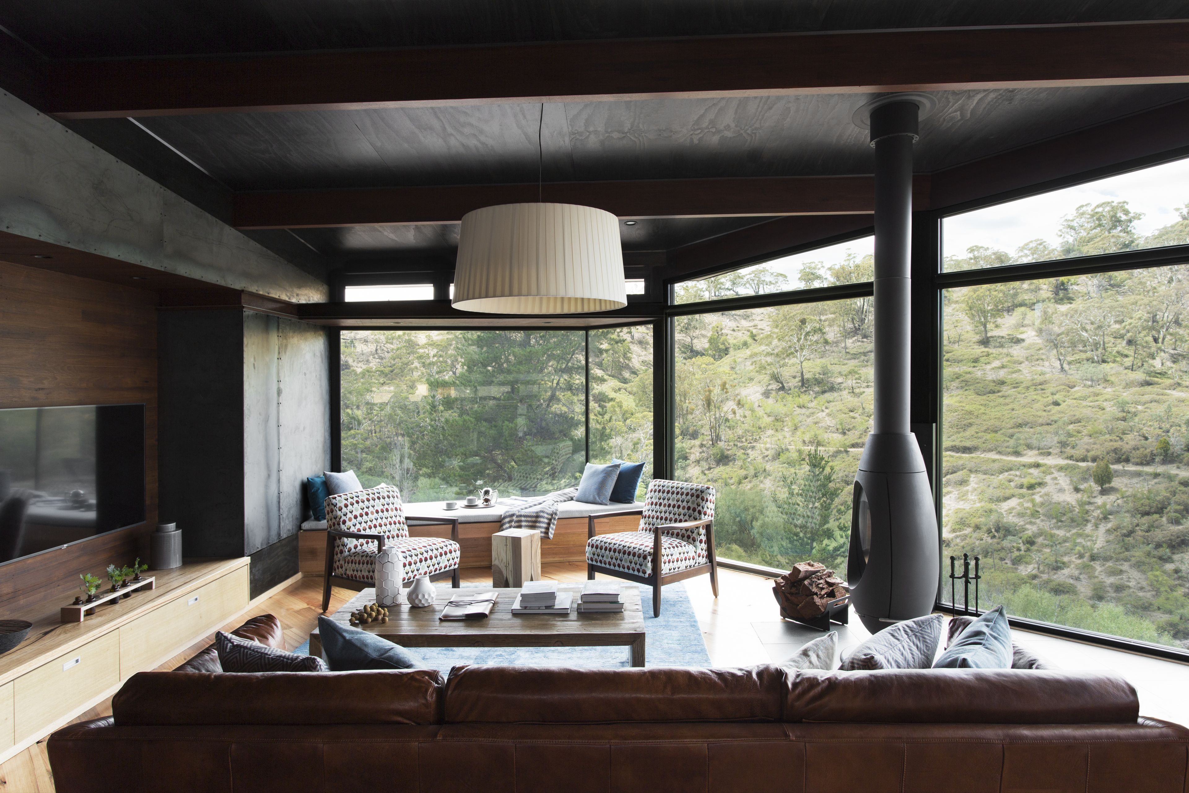 A modern living room with a large window, a fireplace, and a cozy seating area.