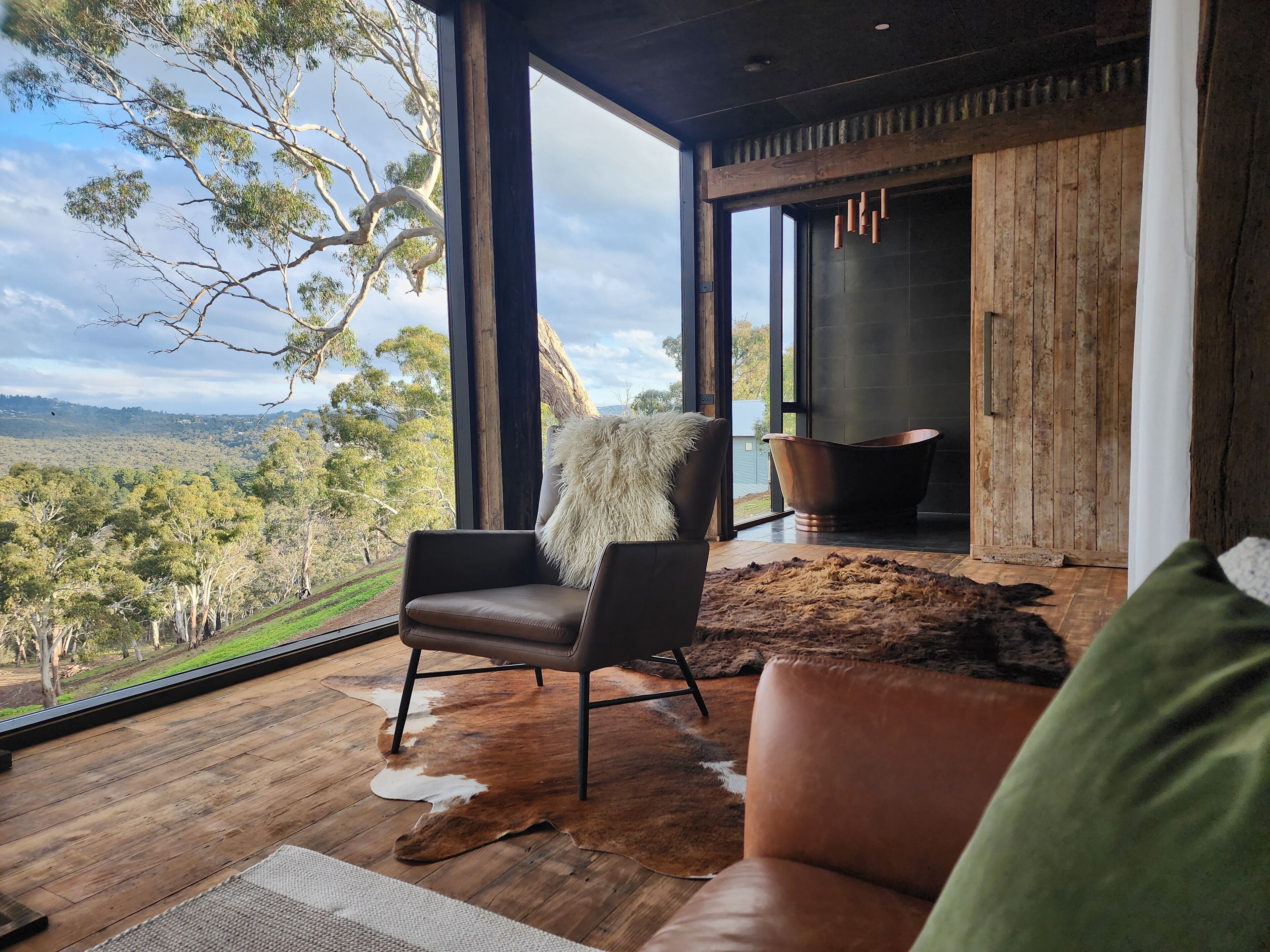 Interior moderno com uma grande janela que oferece uma vista panorâmica de uma paisagem arborizada.