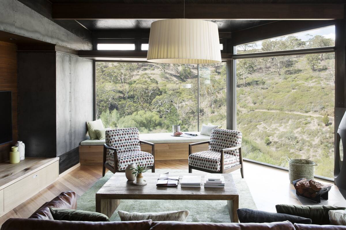 A modern living room with a large window, two patterned chairs, a coffee table, and a sofa.