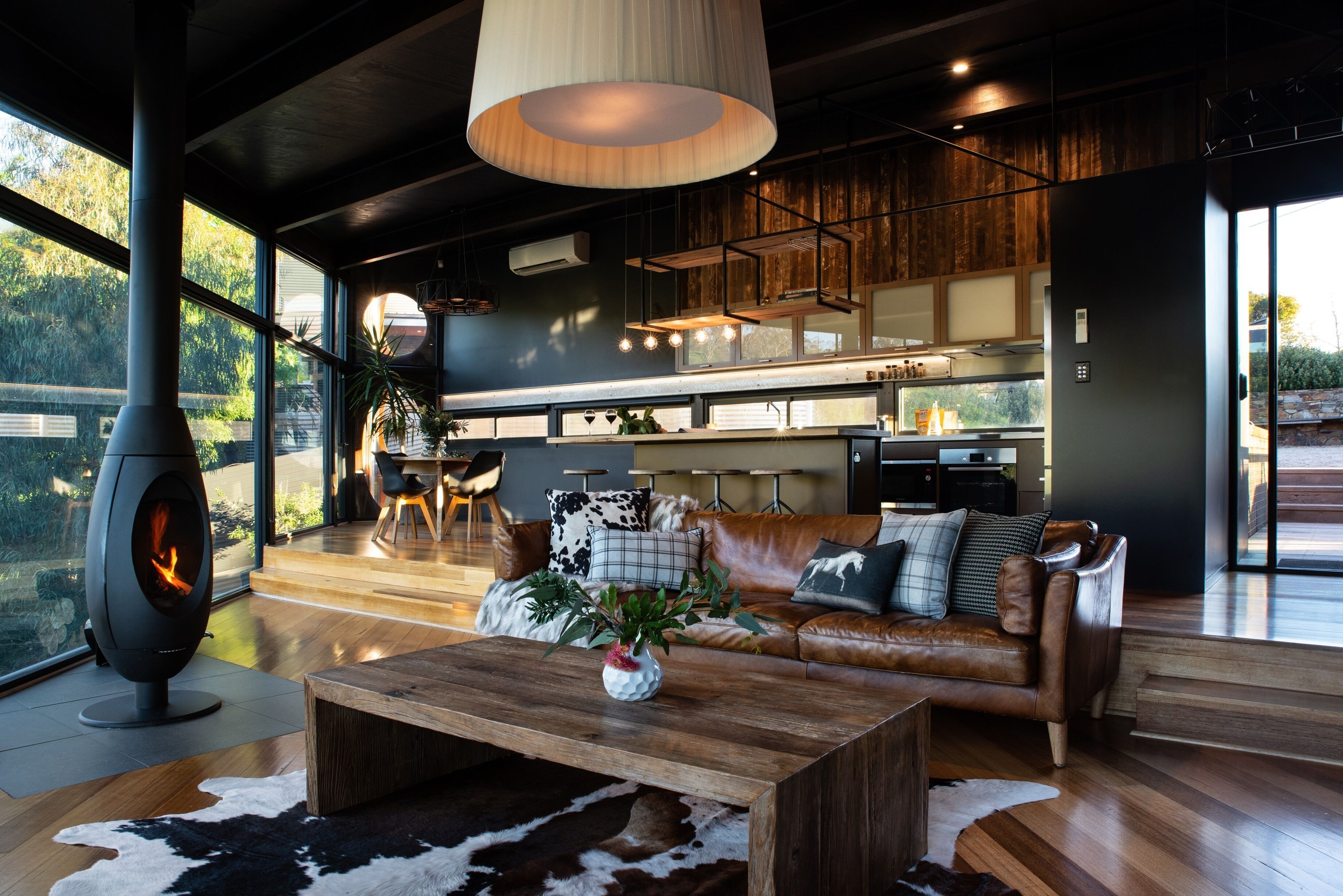 Un salon moderne avec une grande cheminée, un canapé en cuir et une table basse en bois.