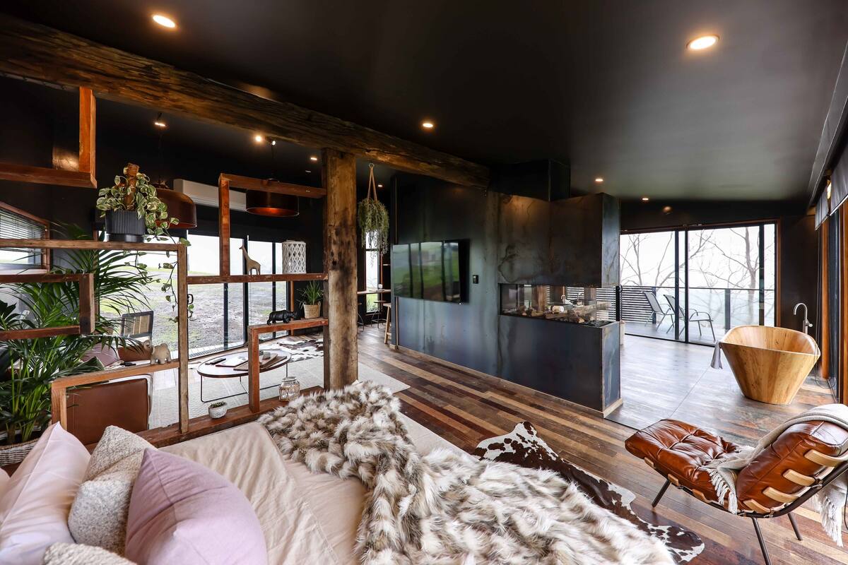 A modern living room with a large fur throw, wooden furniture, and a view of the outdoors.