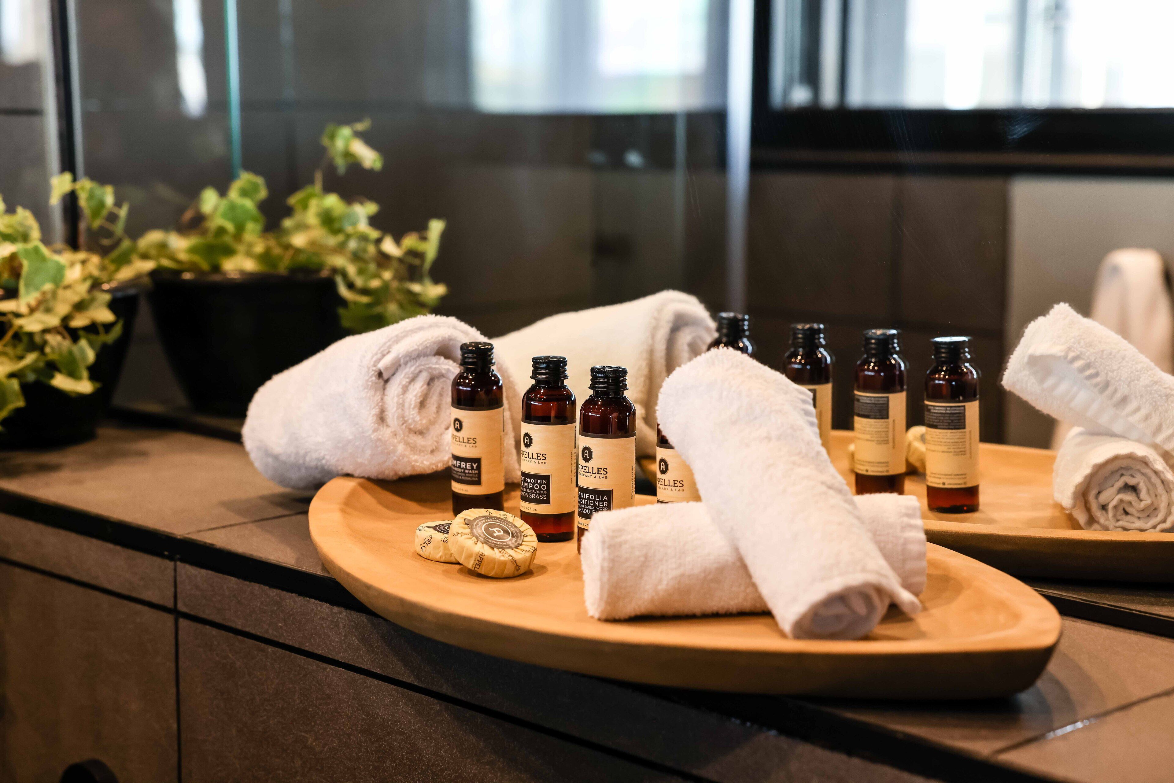A bathroom counter with toiletries, towels, and a plant.