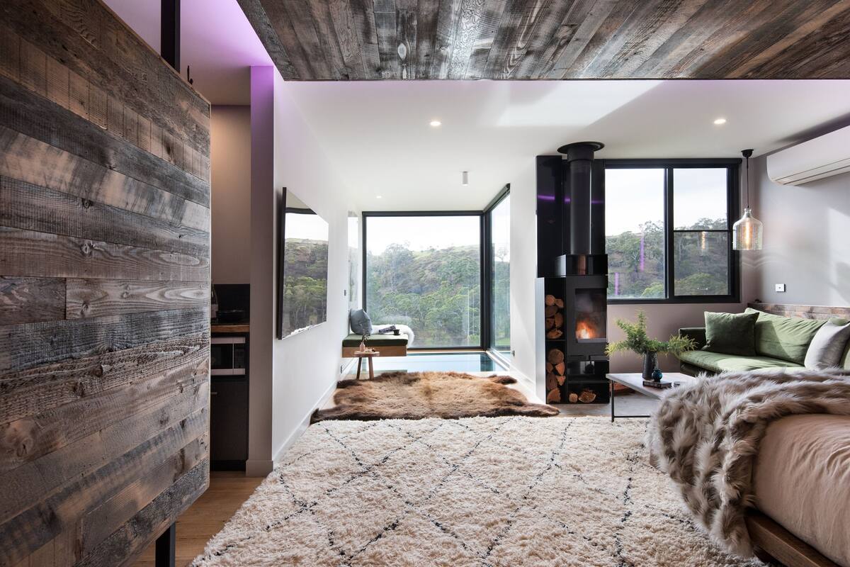 A modern interior with a large window, a fireplace, and a cozy seating area.