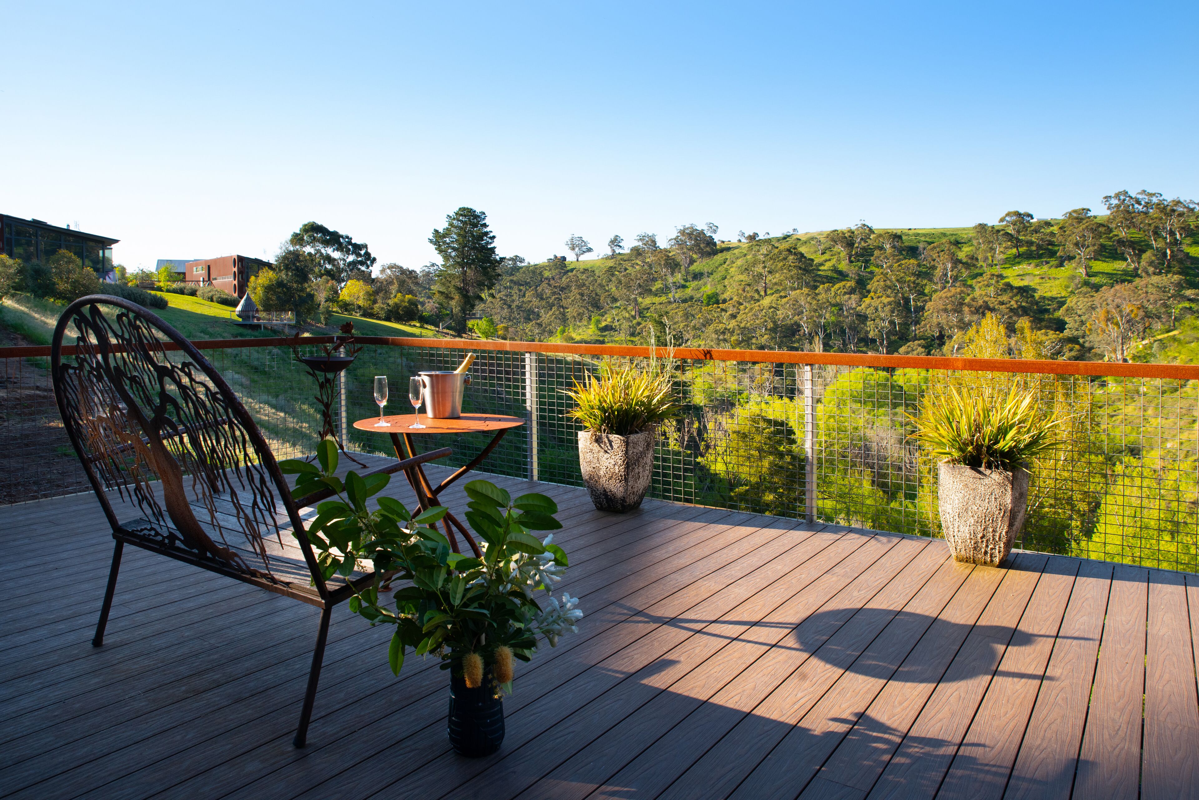 A wooden deck with a metal chair, a small table, and potted plants.