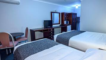 A hotel room with two beds, a desk with a computer, a chair, a small table, and a microwave.