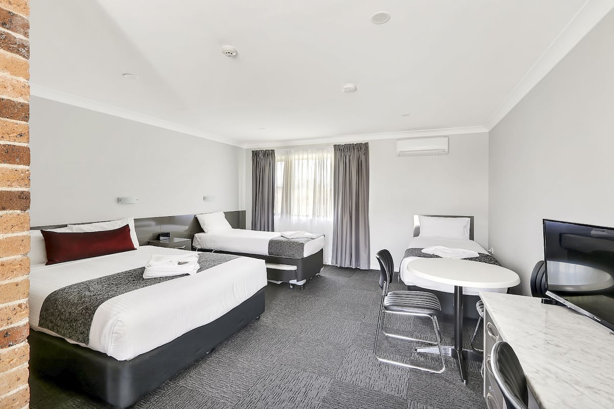 Una habitación de hotel con dos camas, un escritorio, una silla y un televisor.