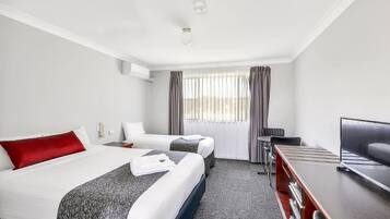 Ein Hotelzimmer mit zwei Betten, einem Schreibtisch, einem Stuhl und einem Fernseher.