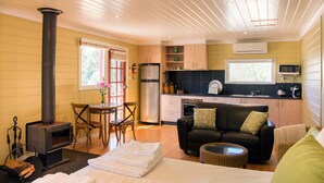 A cozy room with a fireplace, a sofa, a dining table, and a kitchen area. - Avalon Private Spa Villa - Adults Only (Elevated Plains)