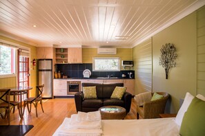 Een compacte woonruimte met een kitchenette, een eethoek en een zithoek met een bank en stoelen.