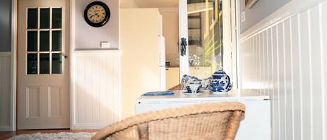 A room with a white door, a wall clock, a mirror, and a table with blue and white vases.
