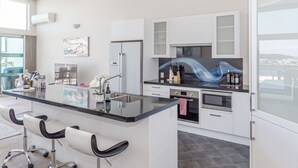 Eine moderne Küche mit einer zentralen Kochinsel, weißen Schränken, einer Mikrowelle und Blick auf die Stadt.