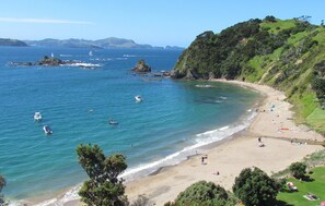 Di pantai, pasir putih, kursi berjemur, dan payung pantai