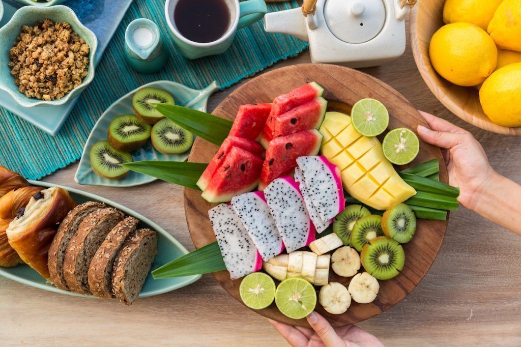 Una mesa de madera con una variedad de frutas, un setero y una taza de café.