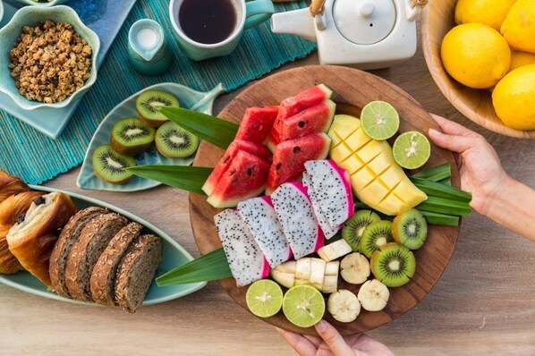 Una mesa de madera con una variedad de frutas, un setero y una taza de café.