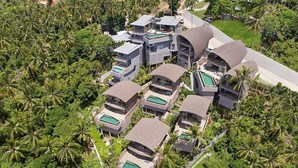 Un complexe hôtelier moderne doté de plusieurs villas, chacune disposant d’une piscine privée et étant entourée d’une végétation luxuriante.