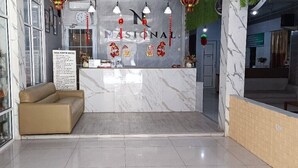 Un área de recepción con mostrador de mármol, un sofá y un cartel.