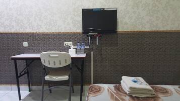A small room with a desk, chair, and a television mounted on the wall.