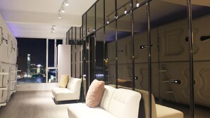 Een moderne hotelkamer met stadszicht, een bank, een witte fauteuil en een glazen scheidingswand.
