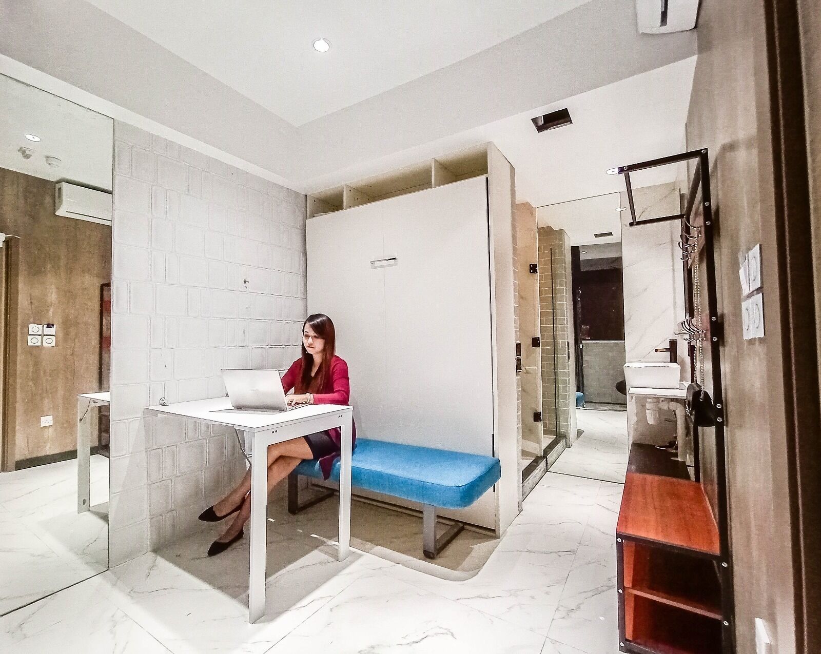 A modern bathroom with a white tiled wall, a glass shower enclosure, and a wooden vanity.