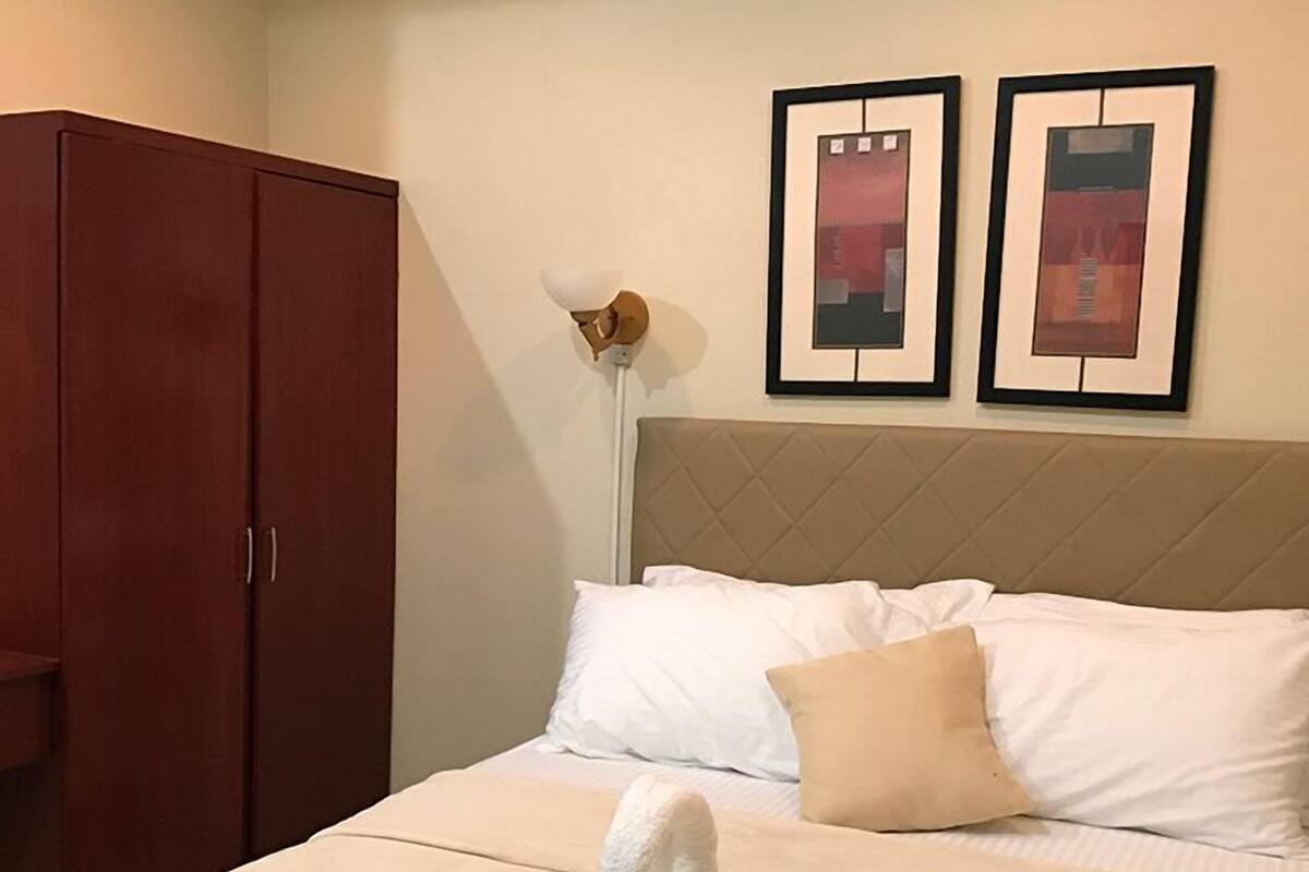 Une chambre d’hôtel avec un lit, une armoire et deux tableaux encadrés accrochés au mur.
