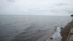 A beach with waves gently lapping onto the shore. - Cabua-an Beach Resort - Hostel (Mambajao)