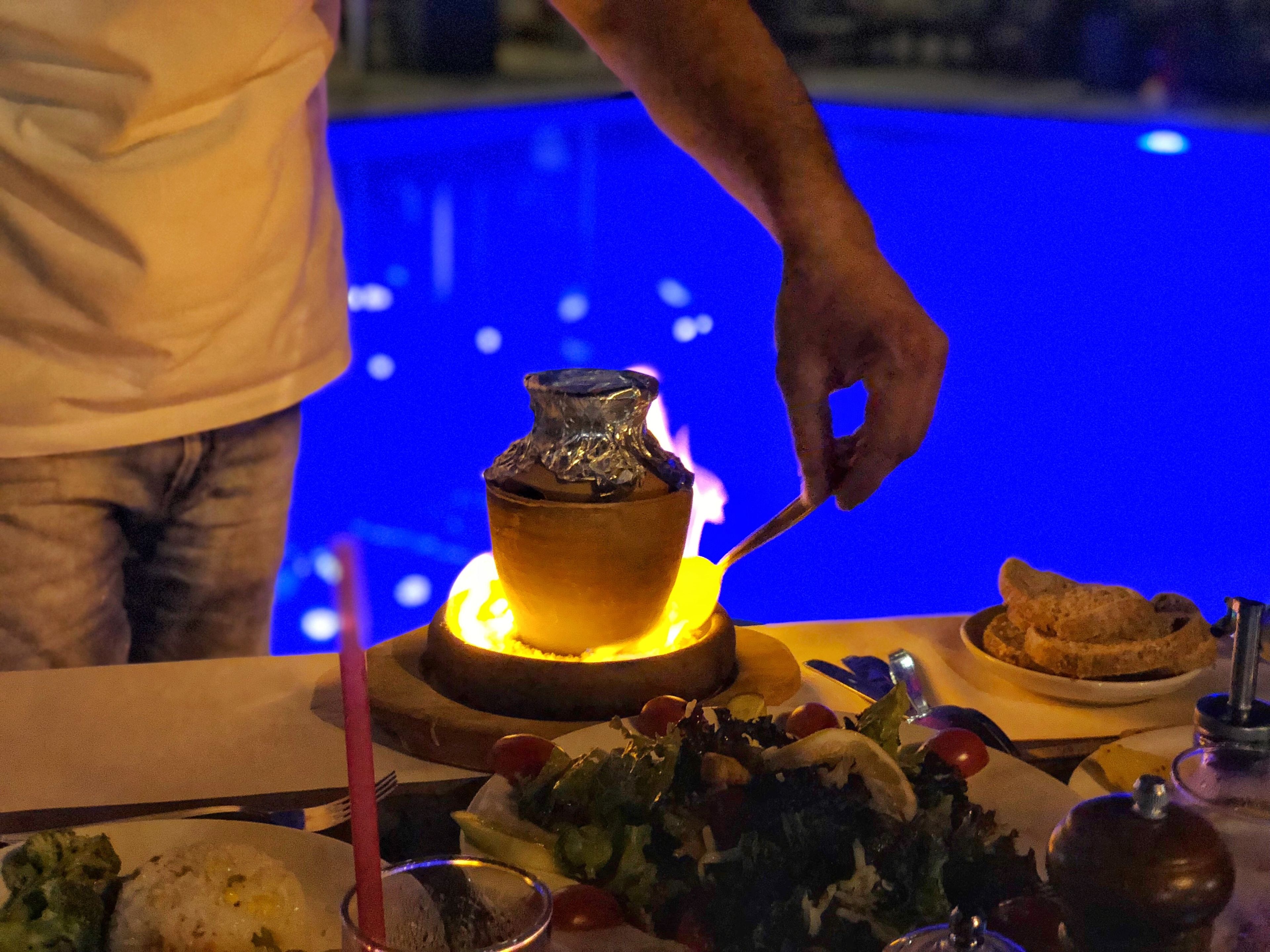Un tavolo da pranzo con un centrotavola illuminato da candele, un'insalata e un piatto di cibo.