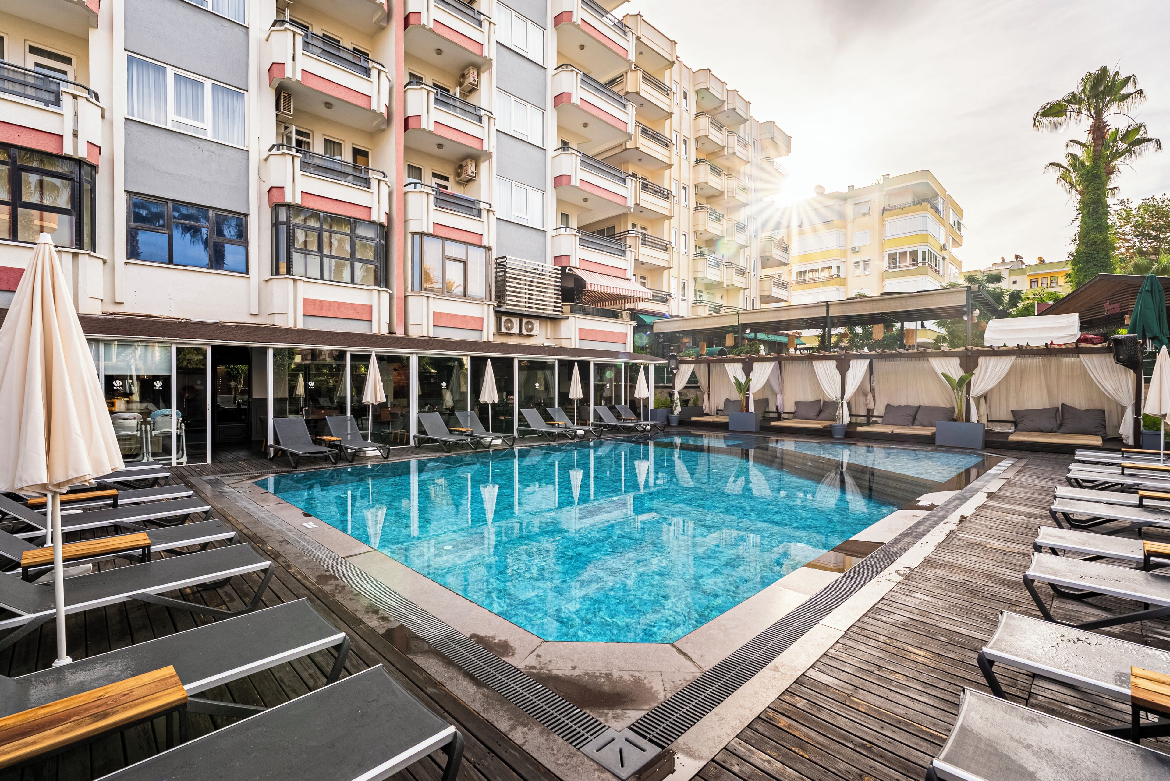 A swimming pool with lounge chairs and umbrellas, surrounded by a wooden deck.