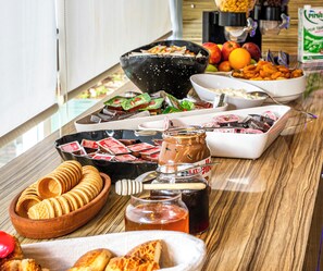 A buffet table with various food items, including waffles, pastries, and condiments. - HMA Hotel & Suites (Alanya)