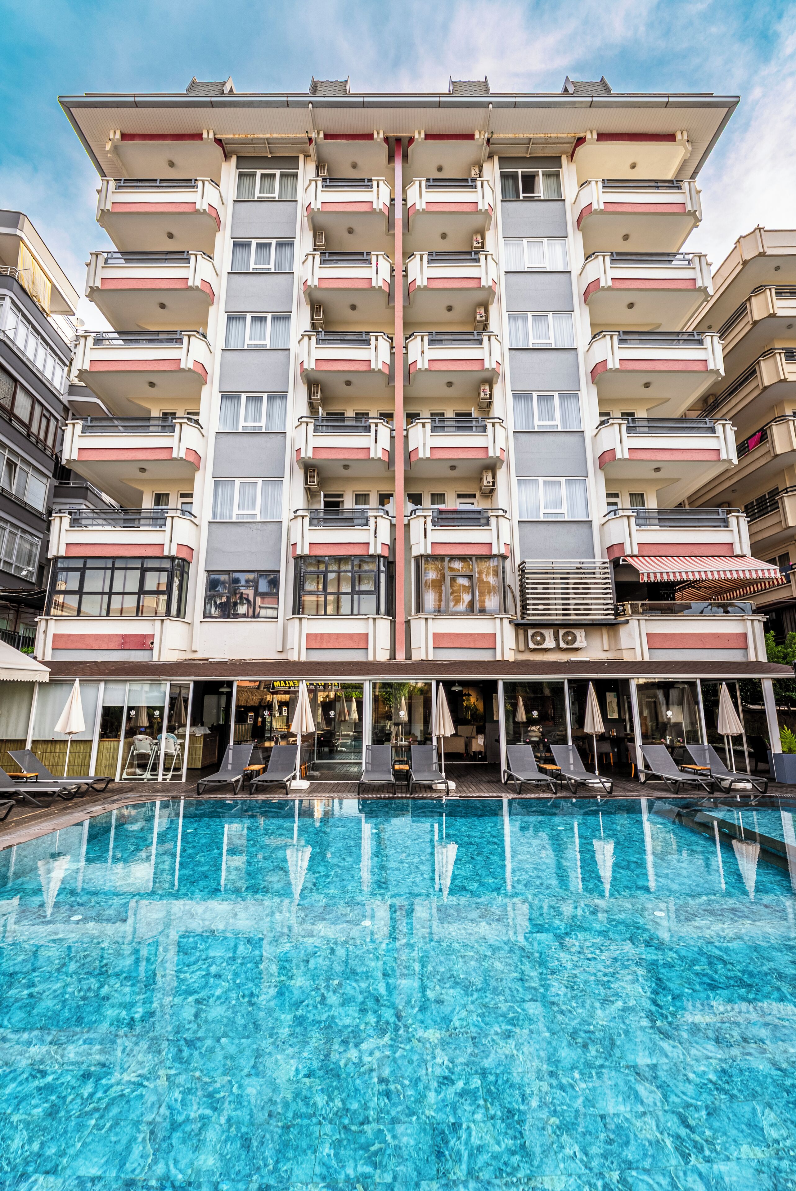 A multi-story hotel with a swimming pool, balconies, and outdoor seating.