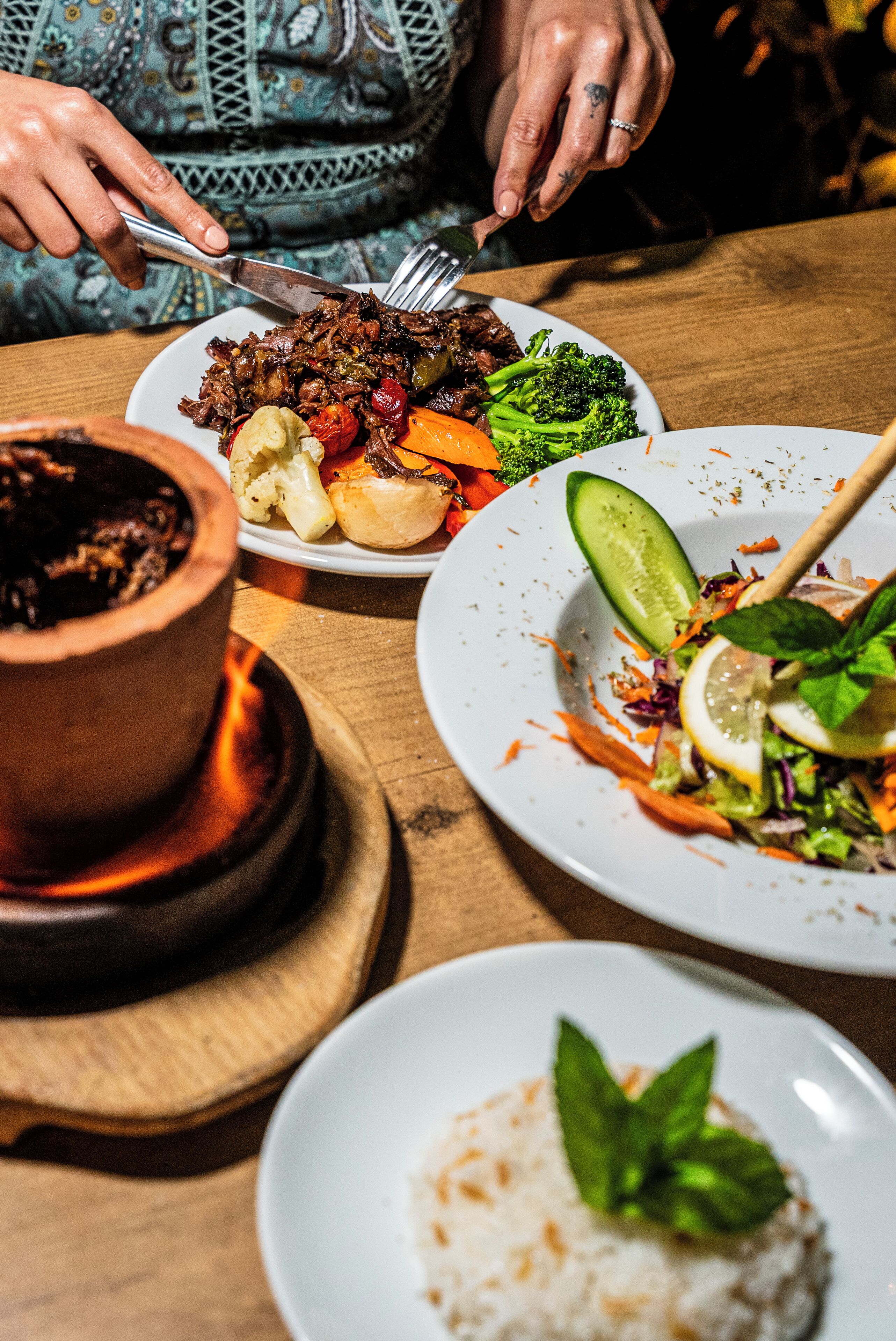 A dining table with various dishes, including a bowl of soup, a plate with meat and vegetables, and a plate with a salad.