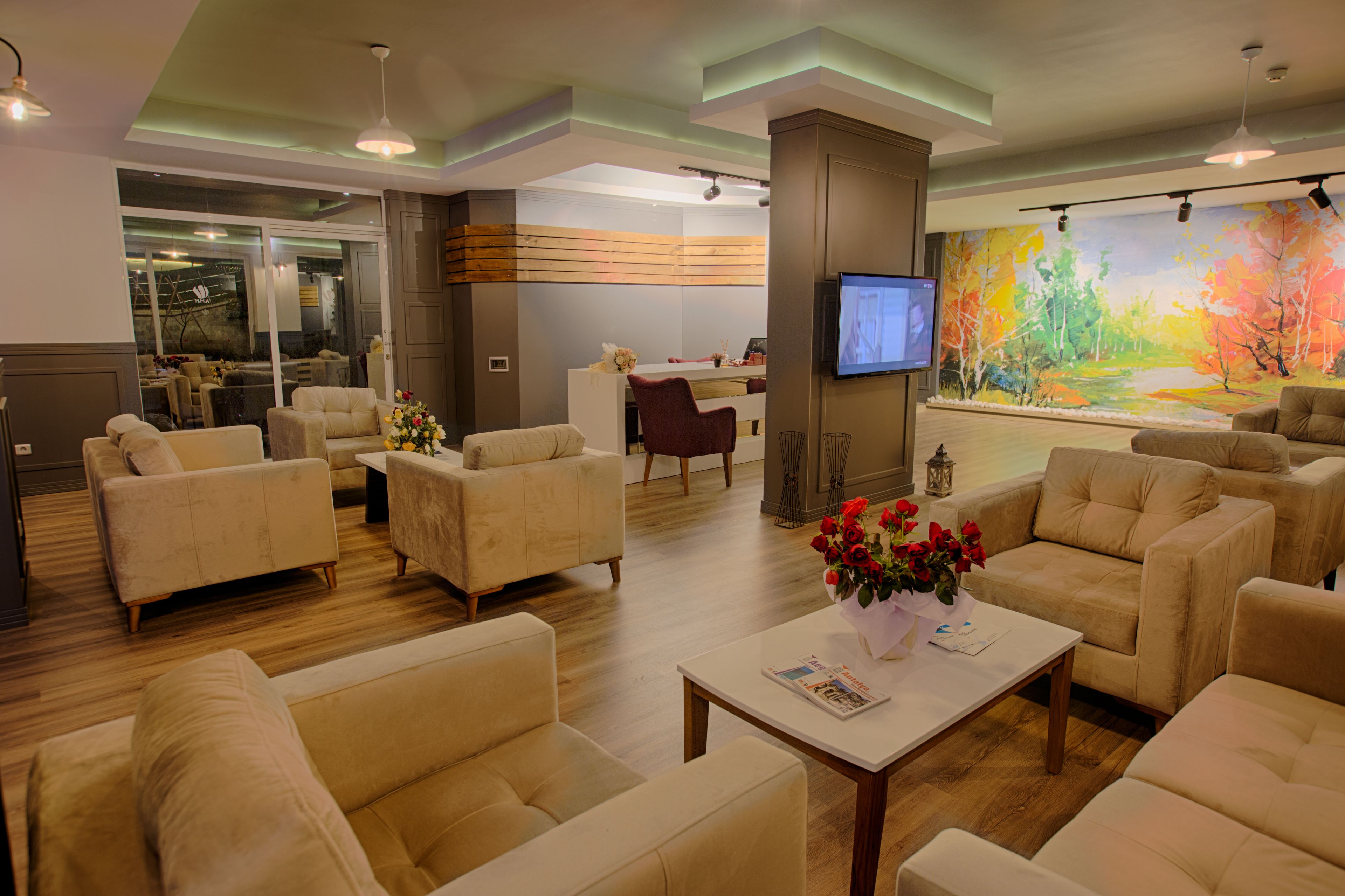 A spacious living area with multiple sofas and a coffee table, a TV mounted on the wall, and a large painting.