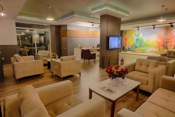 A spacious living area with multiple sofas and a coffee table, a TV mounted on the wall, and a large painting. - HMA Hotel & Suites (Alanya)