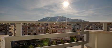 A balcony with a view of a cityscape and a mountain in the distance.