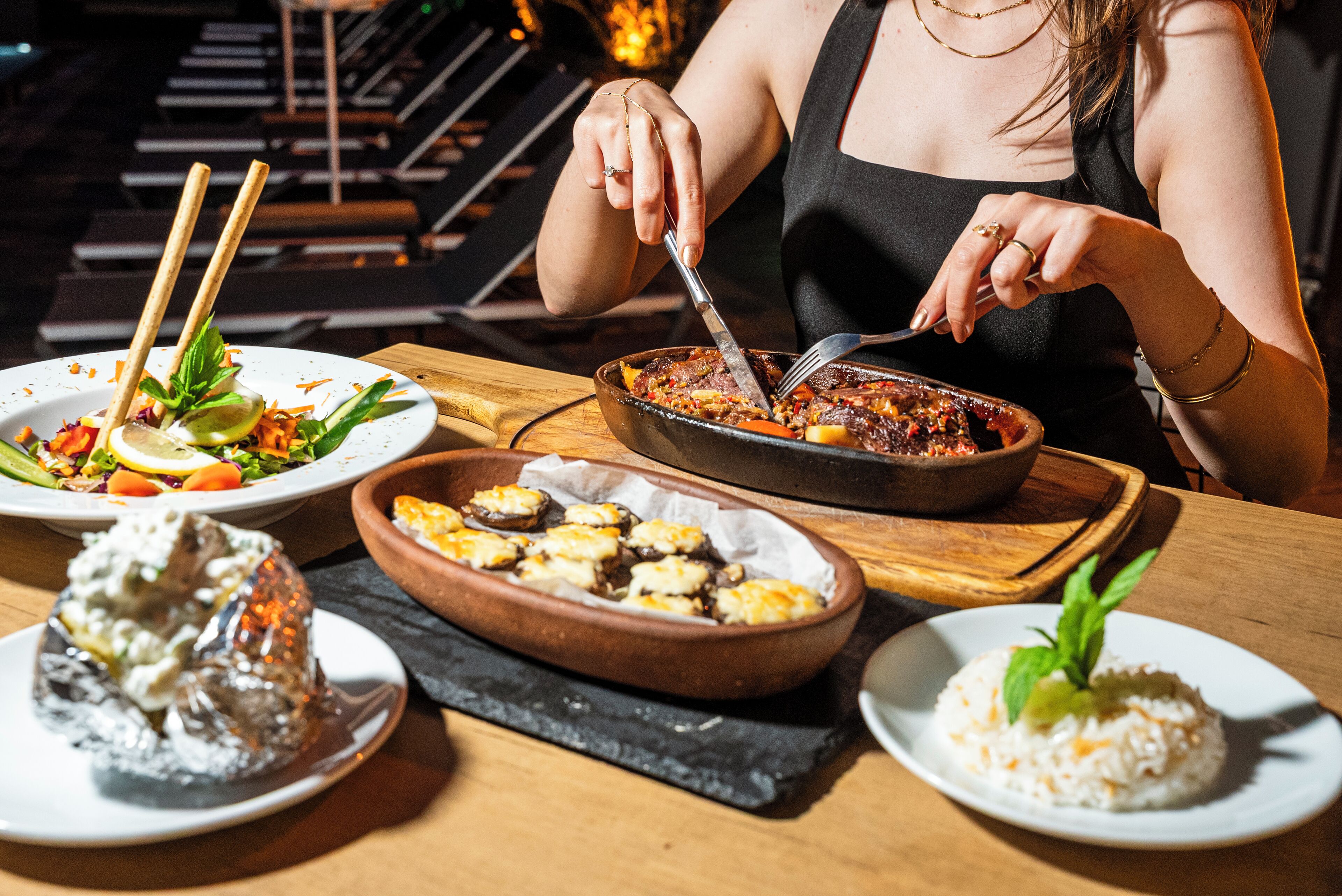 A dining table with various dishes including a salad, a bowl of rice, and a pan of food.