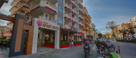Un hotel de varios pisos con un letrero que dice 'HACIENCI HOTEL' y una 'PART HOUSE' contigua.