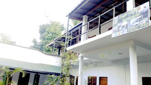 A two-story building with a balcony, signs advertising safari jeep and bungalows, and a covered area with a metal roof. - Eagle Safari Family Bungalow Udawalwe (Udawalawa)