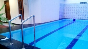 A swimming pool with a metal ladder and a tiled wall. - Eagle Safari Family Bungalow Udawalwe (Udawalawa)