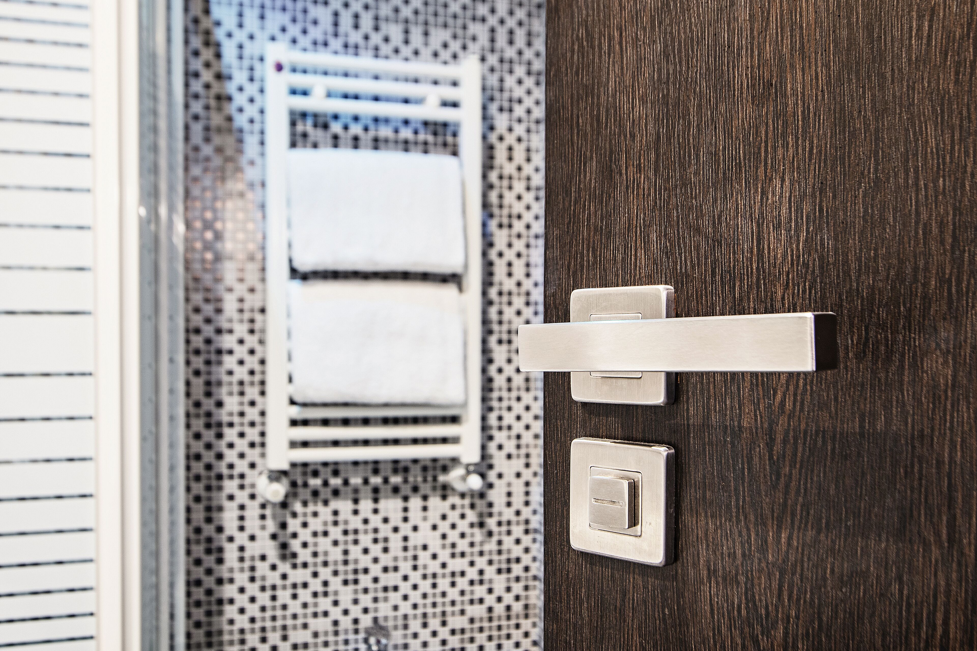 A bathroom with a wooden door, a towel rack, and a thermostat.