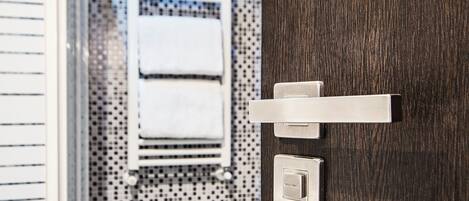 A bathroom with a wooden door, a towel rack, and a thermostat.