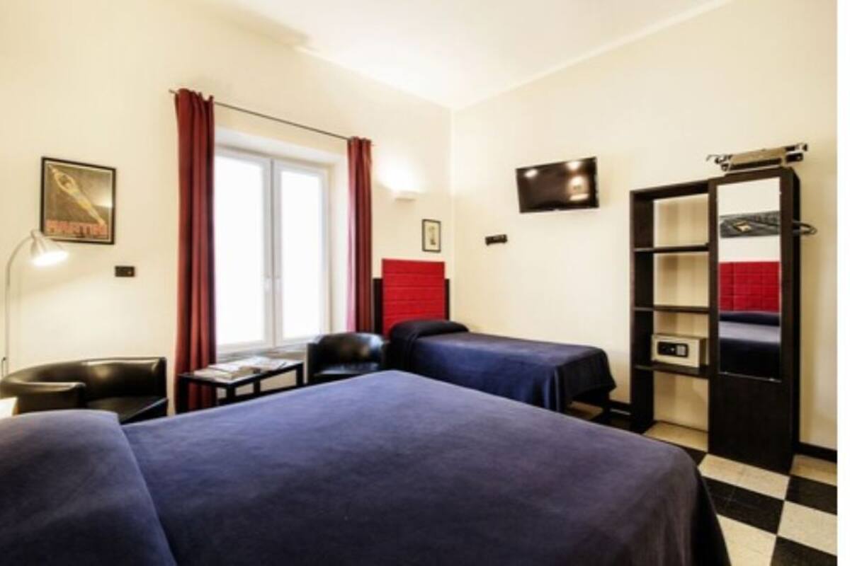 A hotel room with two beds, a desk, a chair, a TV, and a wardrobe.