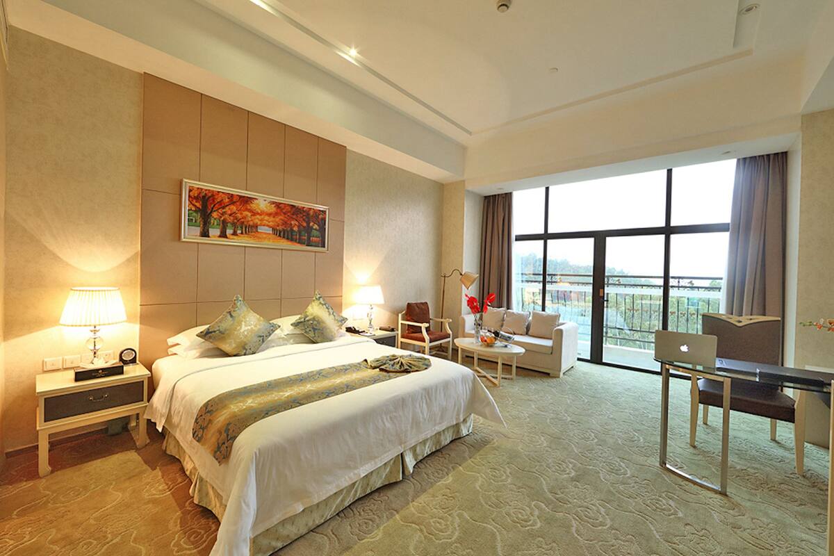 Une chambre d’hôtel avec un grand lit, un bureau, une chaise, un canapé et une vue sur la ville.