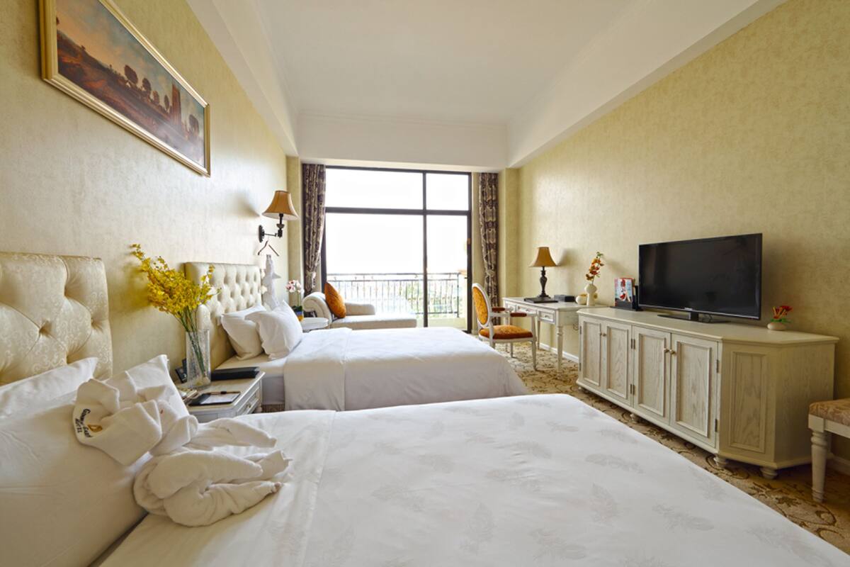 Une chambre d’hôtel avec deux lits, une télévision, un bureau et un balcon avec vue.